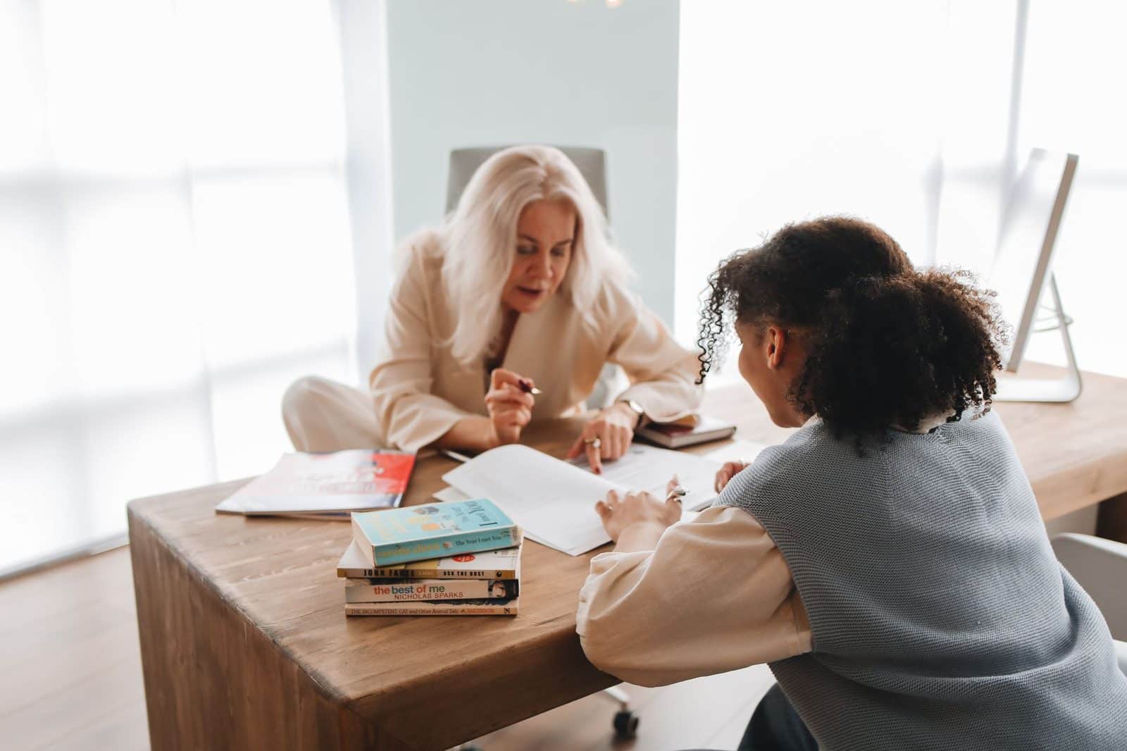 Tutor and student working together at a table with books and notes