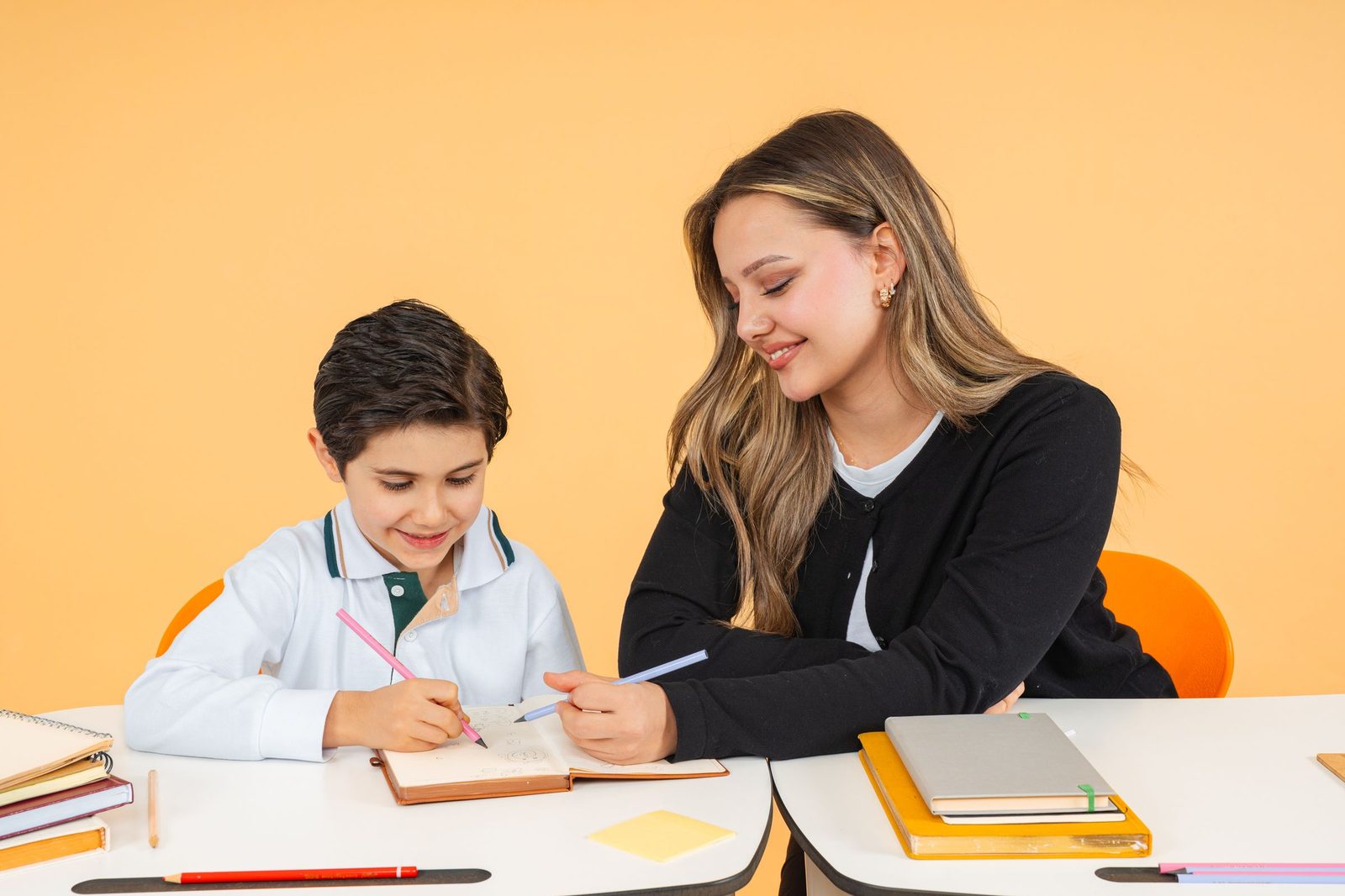 One-on-one tutor helping a young student write in his notebook at a study table