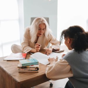Tutor and student working together at a table with books and notes